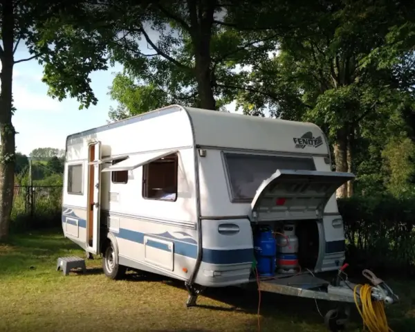 Przygotowania do wypoczynku na **camping Duszniki Zdrój**. Przyczepa kempingowa z otwartym bagażnikiem, w którym widać butle gazowe.