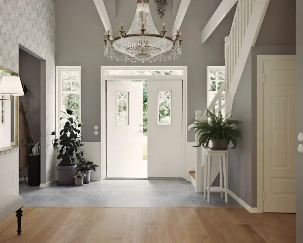 Välkomnande hall med dubbeldörrar, kristallkrona och trappa. Gröna växter ger liv åt det inredda utrymmet.