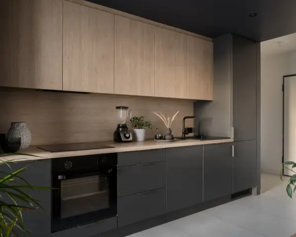 Cocinas de leña modernas con gabinetes de madera clara y encimeras oscuras. Un horno, licuadora y plantas decoran el espacio.