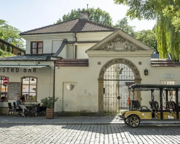 Kazimierz, Kraków. Bistro Bar i zabytkowa brama z hebrajskimi napisami. Obok żółty meleks, idealny na zwiedzanie.