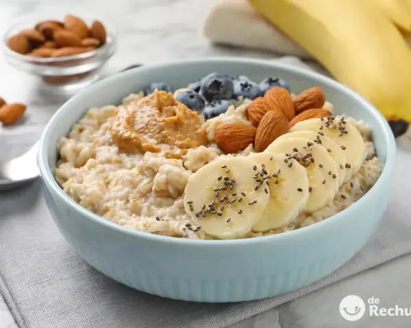 Avena cremosa con plátano, arándanos, almendras y mantequilla de maní. Una guía visual de como cocinar avena para un desayuno nutritivo.