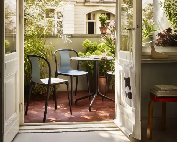 Schmaler Balkon Ideen: Gemütliche Sitzecke mit Tisch und Stühlen, umgeben von üppigem Grün. Perfekt für kleine Räume.
