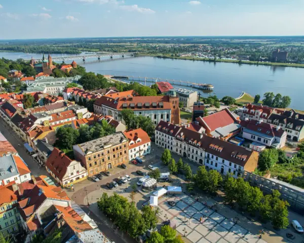 Widok z lotu ptaka na Płock, Wisłę i most. Widać zabytkowe kamienice, katedrę i rynek, które są głównymi atrakcjami w Płocku.