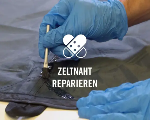 Mit einem Pinsel wird eine schwarze Dichtmasse auf eine Zeltnaht aufgetragen, um sie abzudichten und zu reparieren.