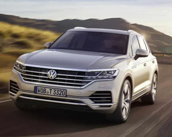Elegancki Volkswagen Touareg, jeden z wielu imponujących volkswagen modele, pędzi po krętej drodze wśród wzgórz.