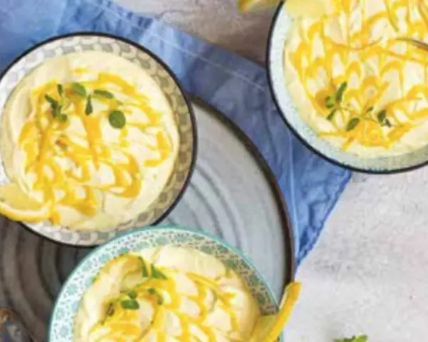Tre coppette di deliziosa mousse al limone, guarnite con scorza di limone e menta fresca.