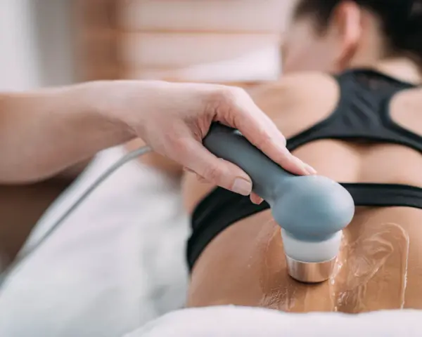 Therapeutin führt Ultraschall Physiotherapie am Rücken einer Patientin durch. Gel auf der Haut für die Behandlung.