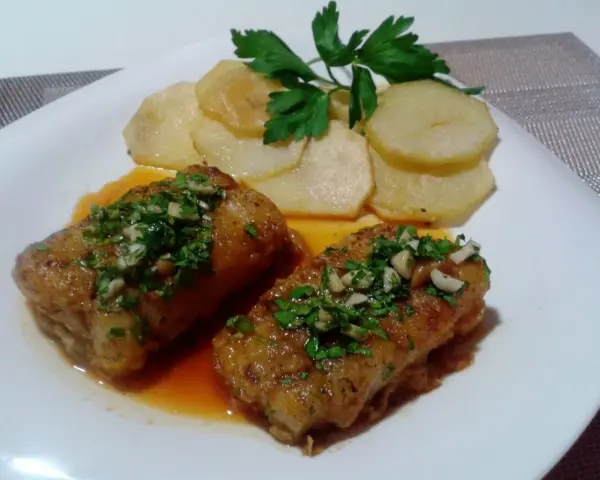 Dos trozos de bacalao a la llauna con patatas y perejil.