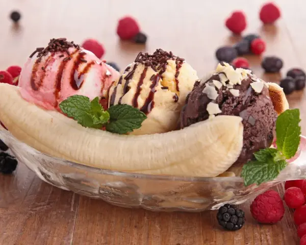 Ein klassisches Banana Split Eis mit drei Kugeln Eis, garniert mit Beeren und Schokostreuseln.