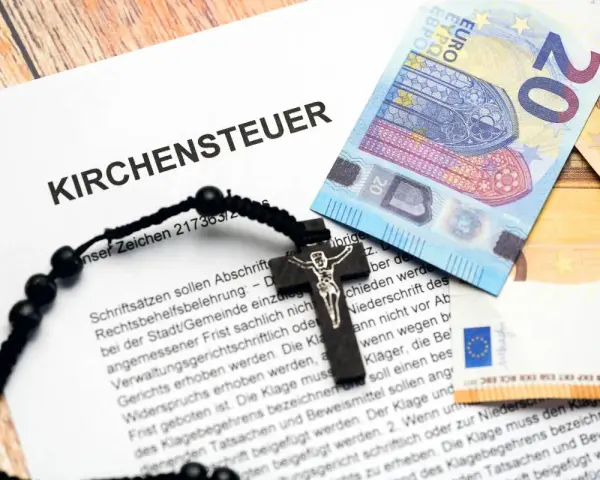 Kirchensteuer-Dokument mit Kreuz und Euro-Scheinen. Lohnt sich Kirchenaustritt finanziell? Die Dokumente und Geldscheine deuten auf eine finanzielle Entscheidung hin.
