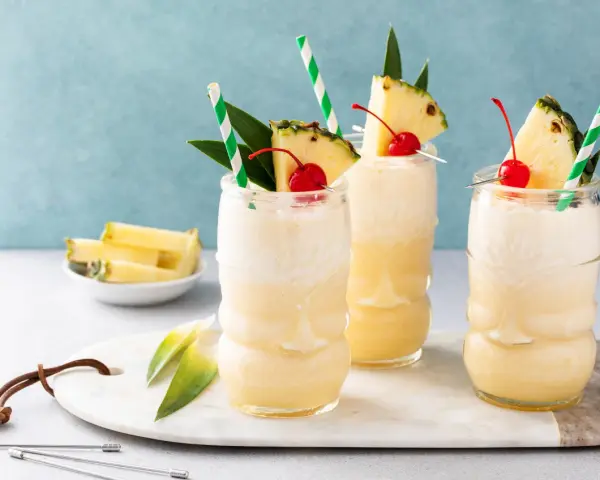 Trzy orzeźwiające drinki bezalkoholowe Mocktail kontra klasyczny koktajl, udekorowane ananasem i wiśnią.