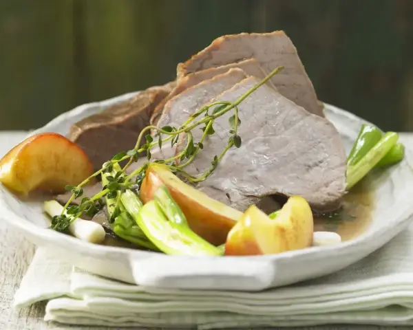 Plastry pieczonej cielęciny z jabłkami, zieloną cebulką i tymiankiem. Idealne połączenie smaków, które podpowiada, jakie przyprawy do cielęciny wybrać.