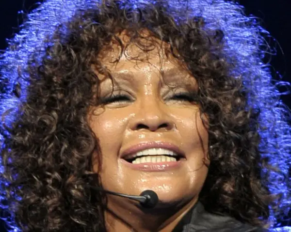 Whitney Houston z zamkniętymi oczami, w pełni emocji, pokazuje niesamowitą **skalę głosu**.