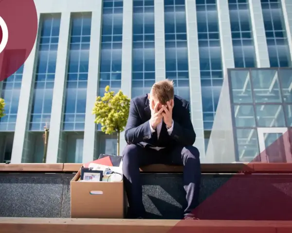 Hombre con caja de pertenencias, sentado frente a un edificio. ¿Me pueden despedir si estoy cubriendo una baja?