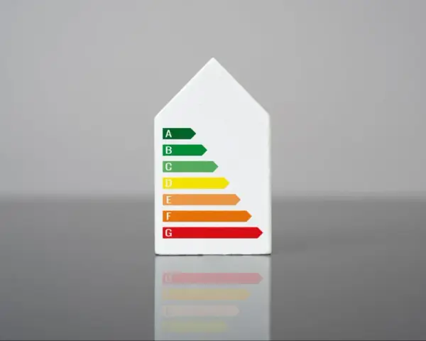 Biały model domu z naklejką klasy energetycznej. Świadectwo energetyczne mieszkania ocenia jego efektywność.
