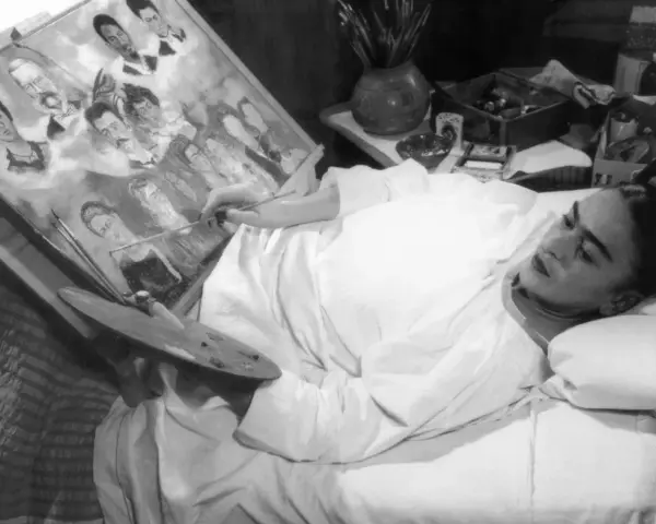 Frida Kahlo målar i sängen, omgiven av sina porträtt av familj och vänner, kanske sina syskon.