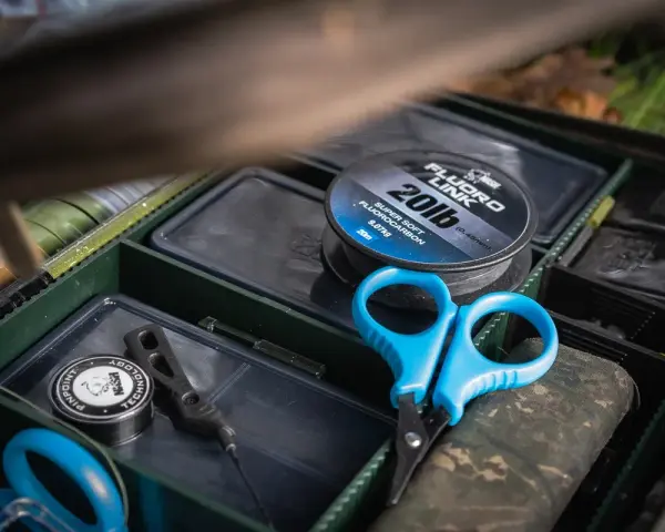 Alles für die beste Karpfenmontage: Fluorocarbon-Schnur, Schere und Zubehör in einer Tacklebox.