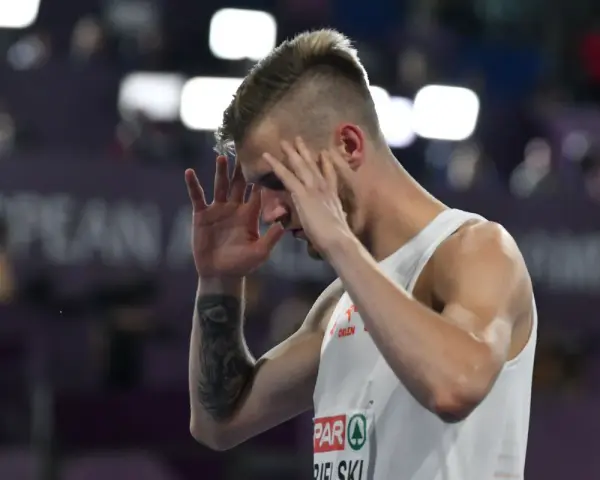 Norbert Kobielski, lekkoatleta, zamyka oczy, skupiając się przed ważnym startem.