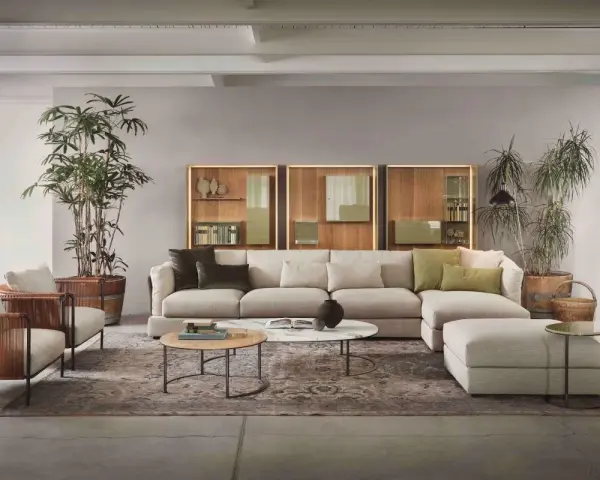 Un salotto moderno con divano componibile color tortora, poltrone in vimini e piante verdi.