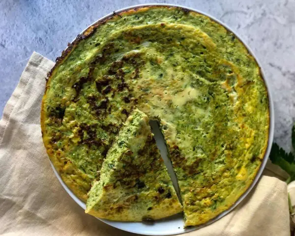 Frittata di zucchine in padella, dorata e profumata, con una fetta tagliata per mostrare la morbidezza interna.