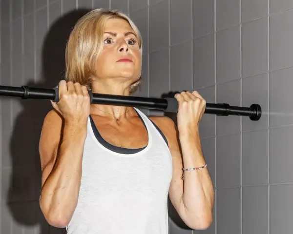 En kvinna med blont hår utför chin ups vid en stång.