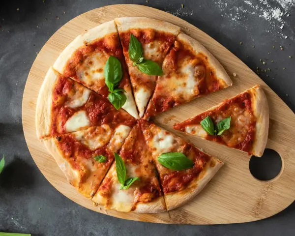 Margherita na desce z drewna. Proste ciasto na pizzę zawsze wychodzi, ozdobione pomidorami, mozzarellą i bazylią.