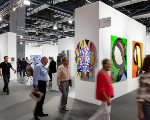 Visiteurs déambulant dans une foire d'art, découvrant des œuvres colorées et des sculptures. On y voit comment fonctionne une galerie d'art : présentation, exposition et interaction.