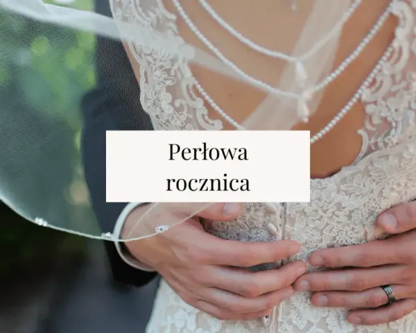 Perłowa rocznica ślubu. Dłonie obejmujące suknię ślubną z koronki i pereł.