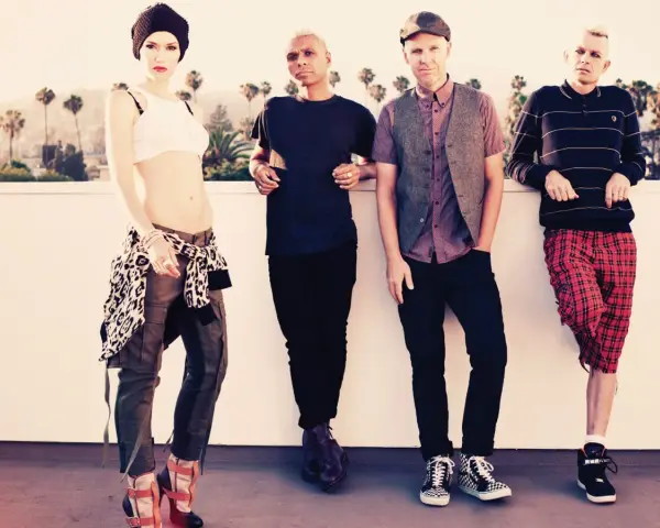 Gwen Stefani und ihre Bandkollegen posieren lässig vor einer Kulisse mit Palmen.