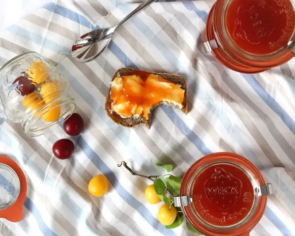Kriecherl-Marmelade auf Brot, Gläser und frische Früchte. Perfekt für leckere Kriecherl Rezepte.