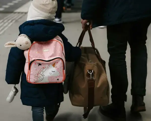 Enfant avec sac à dos licorne et doudou, accompagnant un adulte. Voyage pour une autorisation de sortie de territoire mineur parents séparés.