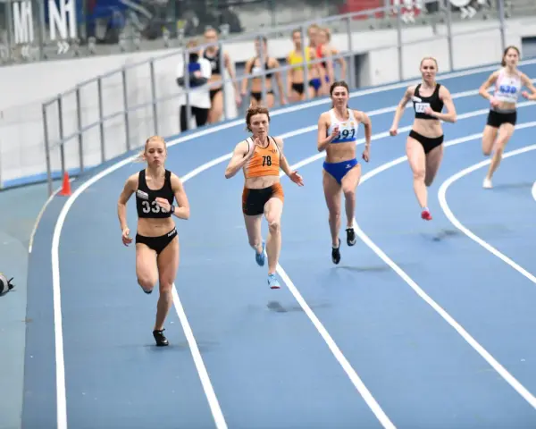 Aneta Lemiesz biegnie w zawodach lekkoatletycznych, walcząc o zwycięstwo na bieżni.