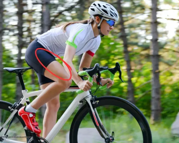 Cyclist experiencing quad pain during a ride, highlighted by a red circle on her thigh.
