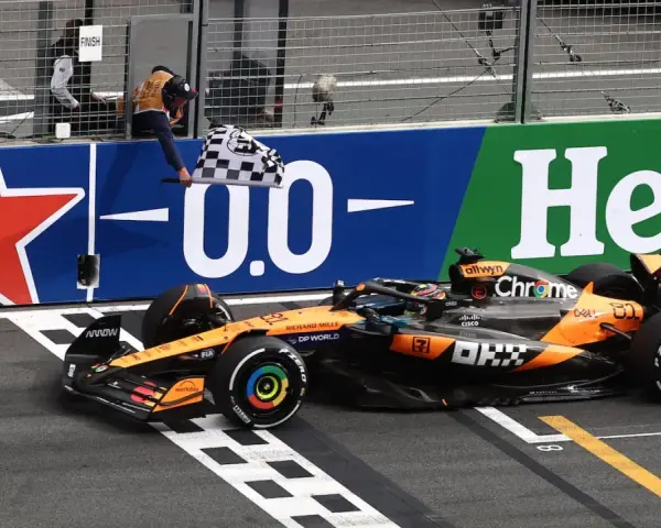 El coche de McLaren cruza la meta en el **Gran Premio Países Bajos**. El piloto celebra la victoria ondeando la bandera a cuadros.