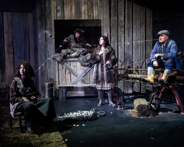 Scena z dramatu. Cztery postacie w wiejskiej scenerii, napięcie w powietrzu. Co to za dramat?