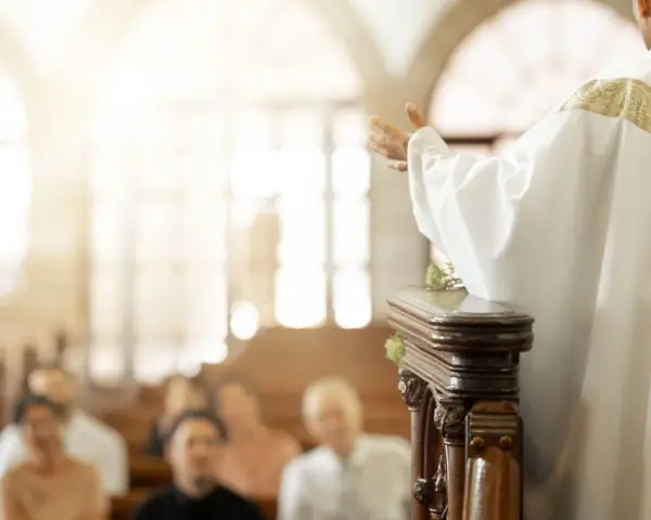 Ksiądz w bieli przemawia do wiernych. W kościele panuje skupienie, jakby każdy zastanawiał się, ile się daje na zapowiedzi.