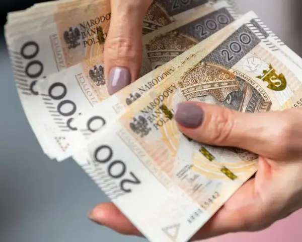 Dłoń trzyma stos banknotów 200 zł. To może być pożyczka od rodziny na nieprzewidziane wydatki.