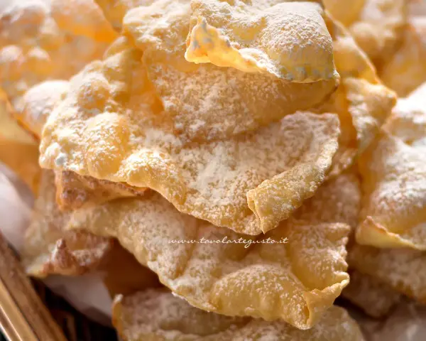 Chiacchiere croccanti, dolci e leggere, come quelle della ricetta della nonna, cosparse di zucchero a velo.