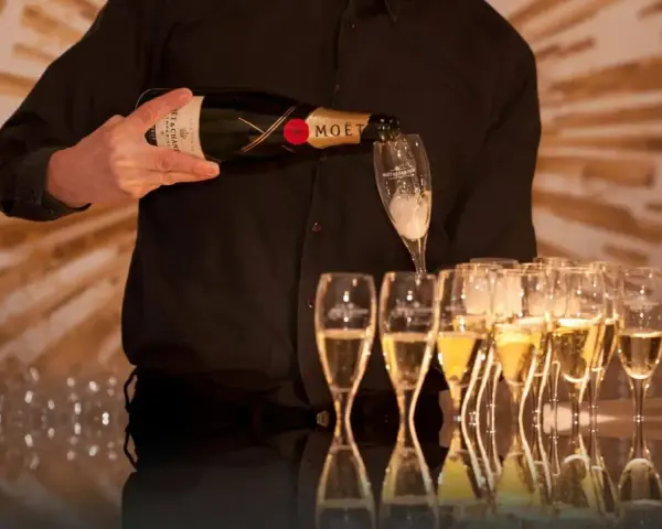 Kelner nalewa szampan Moët & Chandon do kieliszków, przygotowując się do wesela.