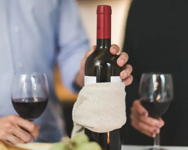 Para świętuje, trzymając butelkę wina. Pamiętaj, wino im starsze tym lepsze.