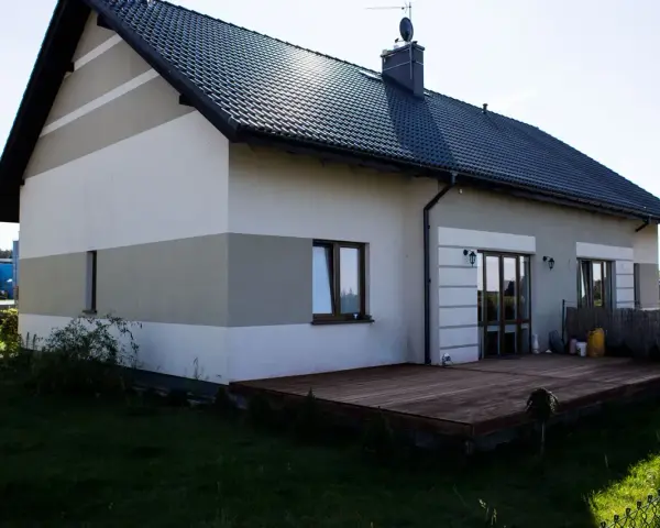 Nowy, dwukolorowy malowanie elewacji domu z drewnianym tarasem.