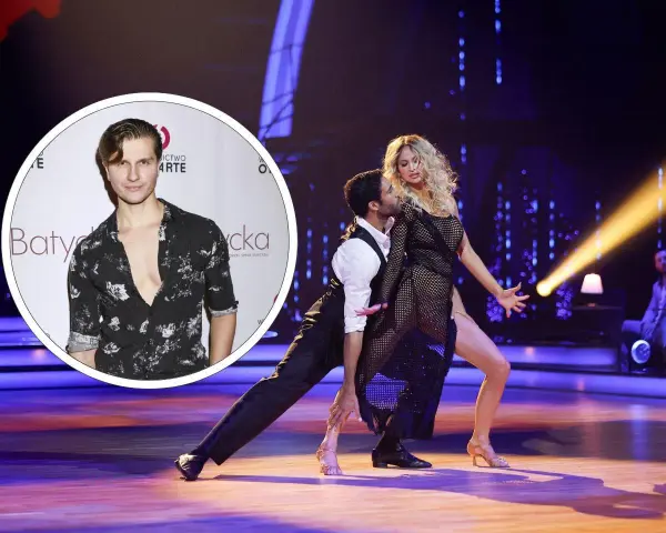 Michał Kassin w stylizacji z głębokim dekoltem, obok tańczącej pary na scenie.