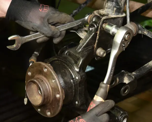 Mechanik wymienia łożysko w Audi A3 8P przód, używając kluczy do demontażu elementów zawieszenia.