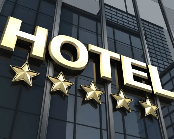 Złote litery "HOTEL" i pięć gwiazdek na nowoczesnym budynku. Spełnia hotel 4 gwiazdki wymagania luksusu i komfortu.