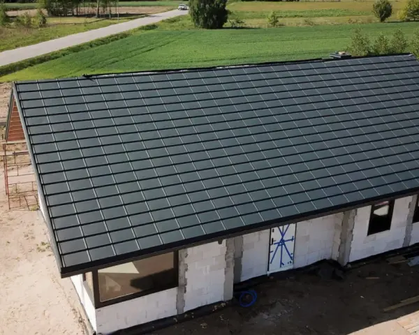 Nowy dom w budowie z ciemnoszarym dachem, widok z góry.