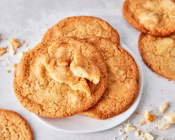 Saftige white chocolate cookies, eine davon angebrochen, mit Stückchen weißer Schokolade und Krümeln daneben.