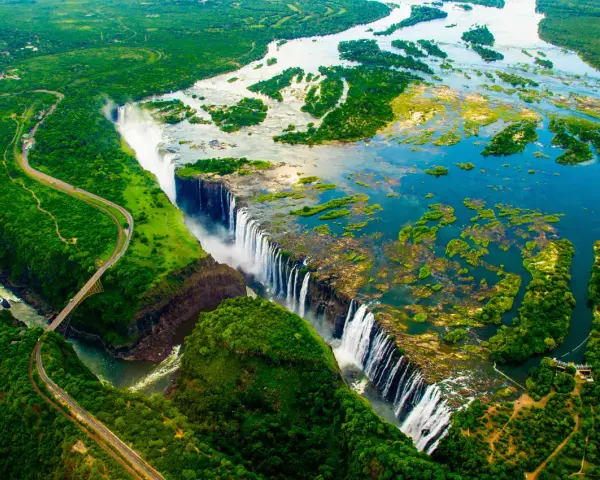 Wodospad Wiktorii, jedna z największych atrakcji Zimbabwe, z lotu ptaka. Potężny nurt rzeki Zambezi spada kaskadami w dół, tworząc mgłę i tęczę.