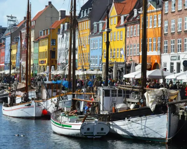 Colorful buildings line a canal in Copenhagen, with boats docked and people enjoying the waterfront. A perfect scene for exploring things to do in Denmark.