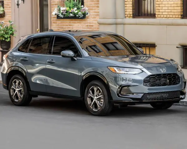 Elegancki, szary SUV Honda HR-V stoi na ulicy przed budynkiem z cegły.