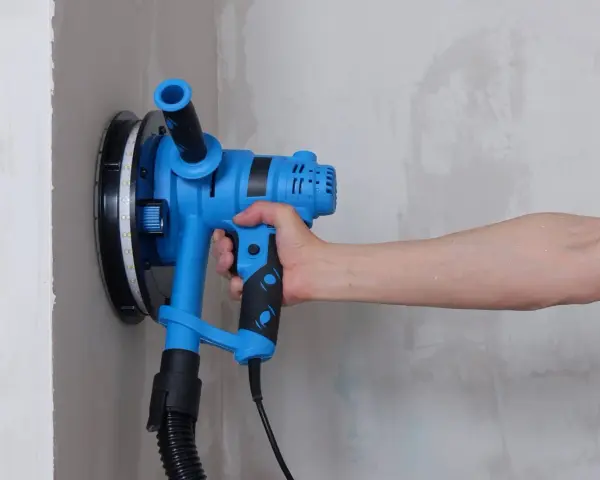 Utensile blu per levigare il muro, ideale per capire come togliere la vernice dal muro.